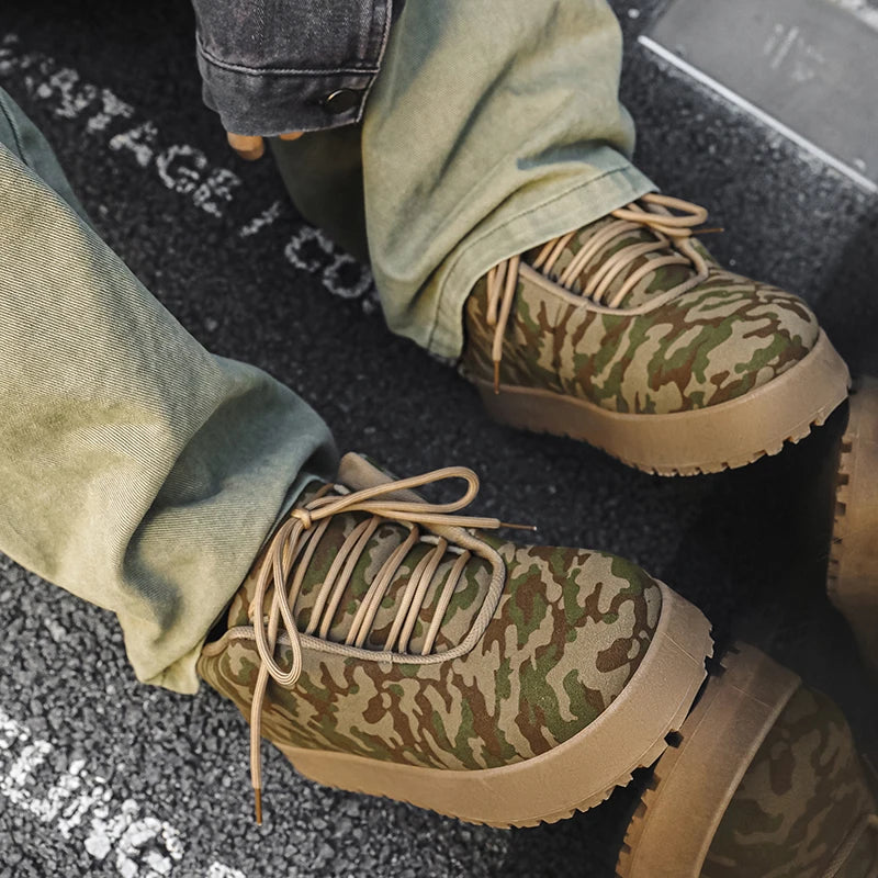 Men’s VOIDWEAR VDR_VANISH_02 shadow winter boots with platform sole, microfiber leather, and ritual-inspired design, styled for urban streetwear, Camouflage boots with beige laces worn with green pants on a dark surface.