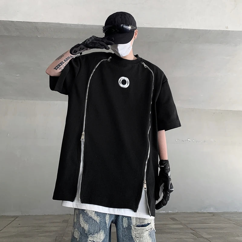 VOIDWEAR SIGNAL_07 padded shoulder oversized tee, double zipper streetwear, ritual-coded glyph sleeve. Person wearing a black oversized t-shirt with a logo, black gloves, and a cap in an indoor setting.
