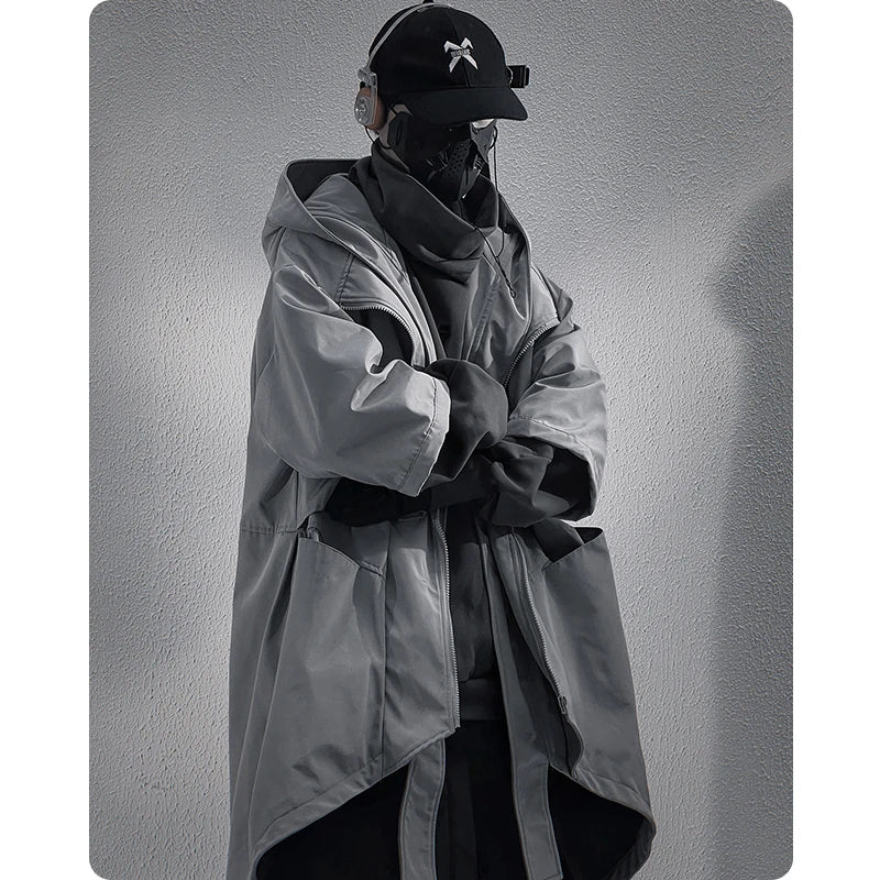 Person wearing a long coat and cap against a plain background. A male model in the Voidwear SIGNAL_VANISH_05 ☰, a minimalist and conceptual mid-sleeved hooded trench coat designed for stylish urban wear in the US and EU.