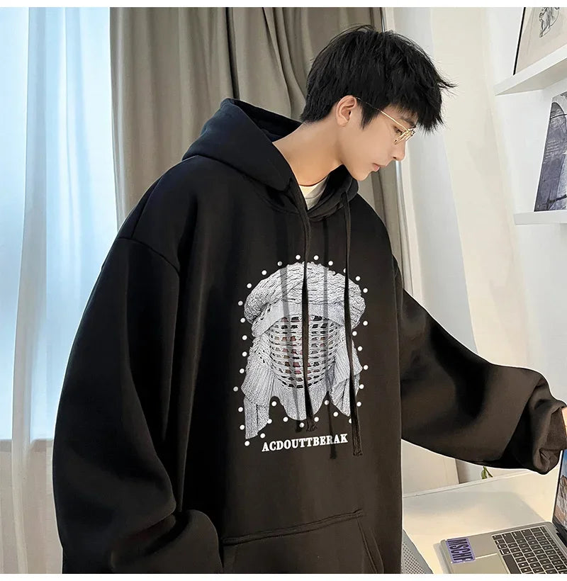 VOIDWEAR VDR_SHDW_07 oversized goth hoodie with masked figure graphic, in black, styled in urban streetwear fit. Person wearing a black hoodie with a white graphic design, sitting at a desk.