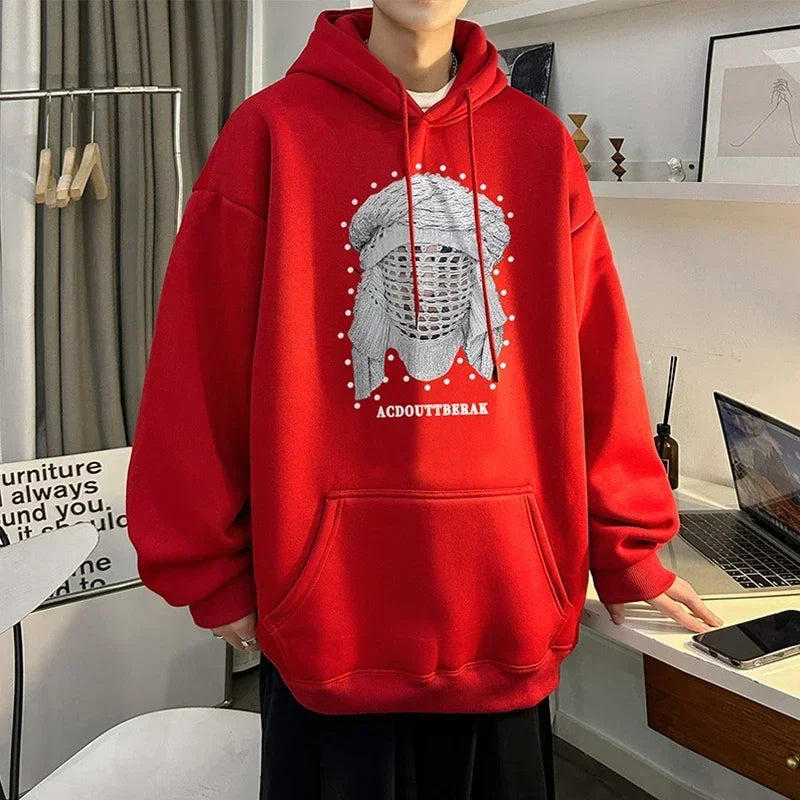 VOIDWEAR VDR_SHDW_07 oversized goth hoodie with masked figure graphic, in black, styled in urban streetwear fit. Person wearing a red hoodie with a graphic design in a room with a laptop and phone on a desk.