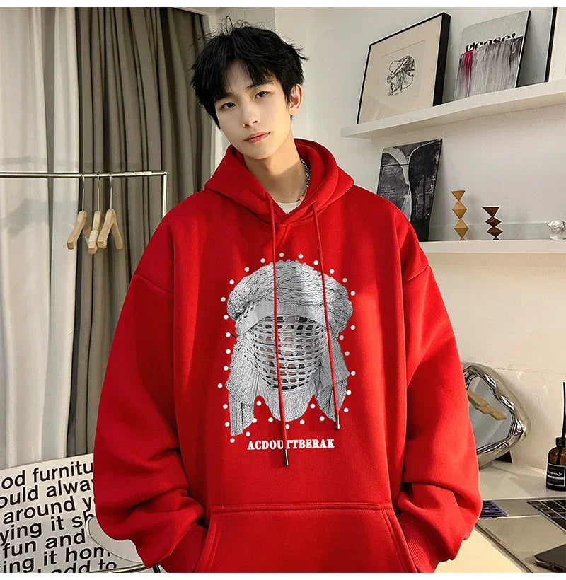 VOIDWEAR VDR_SHDW_07 oversized goth hoodie with masked figure graphic, in black, styled in urban streetwear fit. Person wearing a red hoodie with a graphic design indoors
