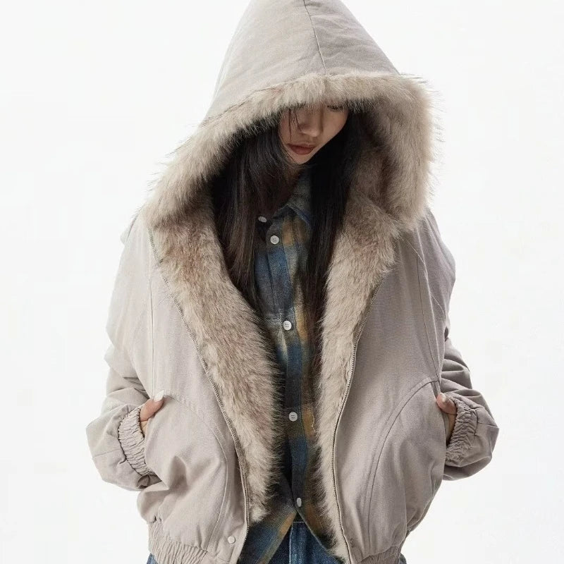 VOIDWEAR™ VDR_25 — a unisex oversized plush hooded jacket. Person wearing a beige hooded jacket with fur trim on a white background