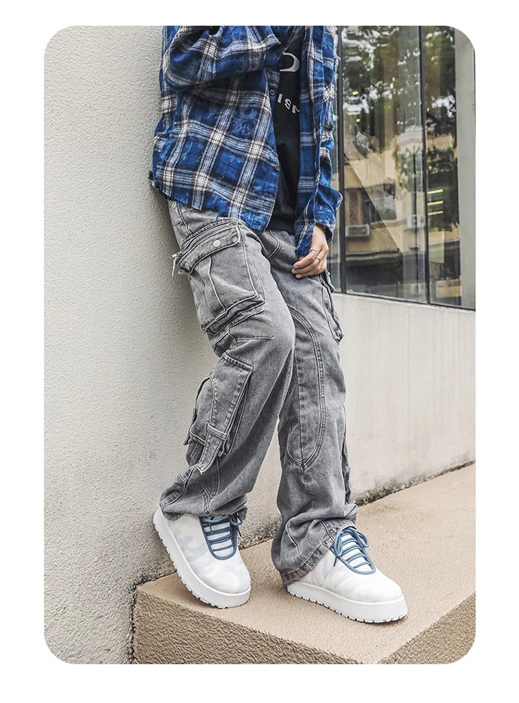 Person wearing gray cargo pants, white sneakers, and a blue plaid shirt leaning against a wall. VOIDWEAR CODE_SYSTEM_07 ⚔️ chunky sneaker-style boots shown on a city street in winter, highlighting the microfiber leather upper and thick platform sole.
