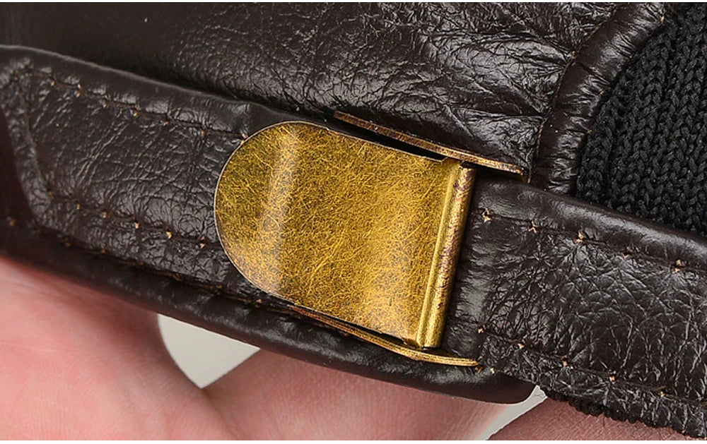 Close-up of a black leather belt with a gold buckle held by a hand.