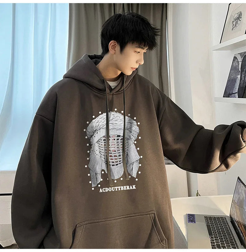 VOIDWEAR VDR_SHDW_07 oversized goth hoodie with masked figure graphic, in black, styled in urban streetwear fit. Person wearing a brown hoodie with a graphic design in an indoor setting