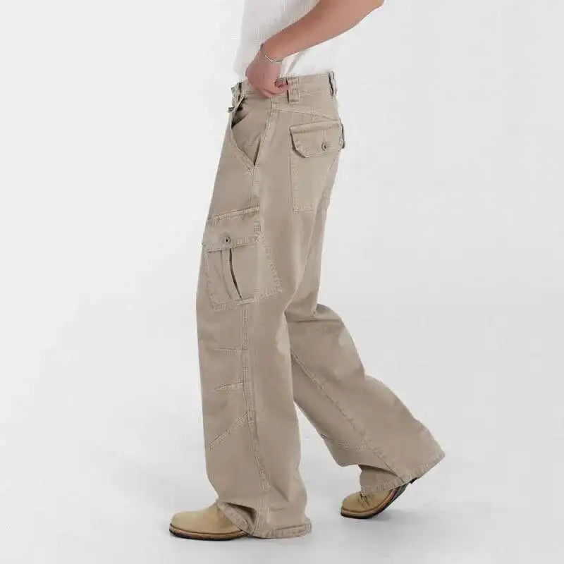Beige cargo pants worn by a person on a white background. Loose-fit midweight cargo denim jeans with signal glyph embroidery and vanish-mode stitching for men