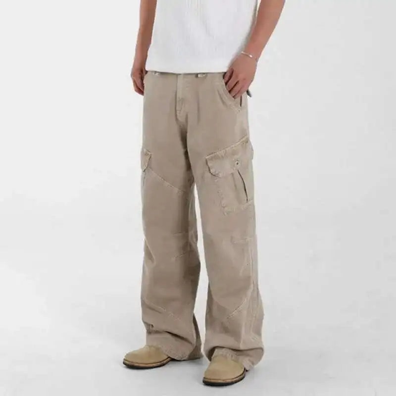 Person wearing beige cargo pants on a white background. VDR_Loose-fit midweight cargo denim jeans with signal glyph embroidery and vanish-mode stitching for men