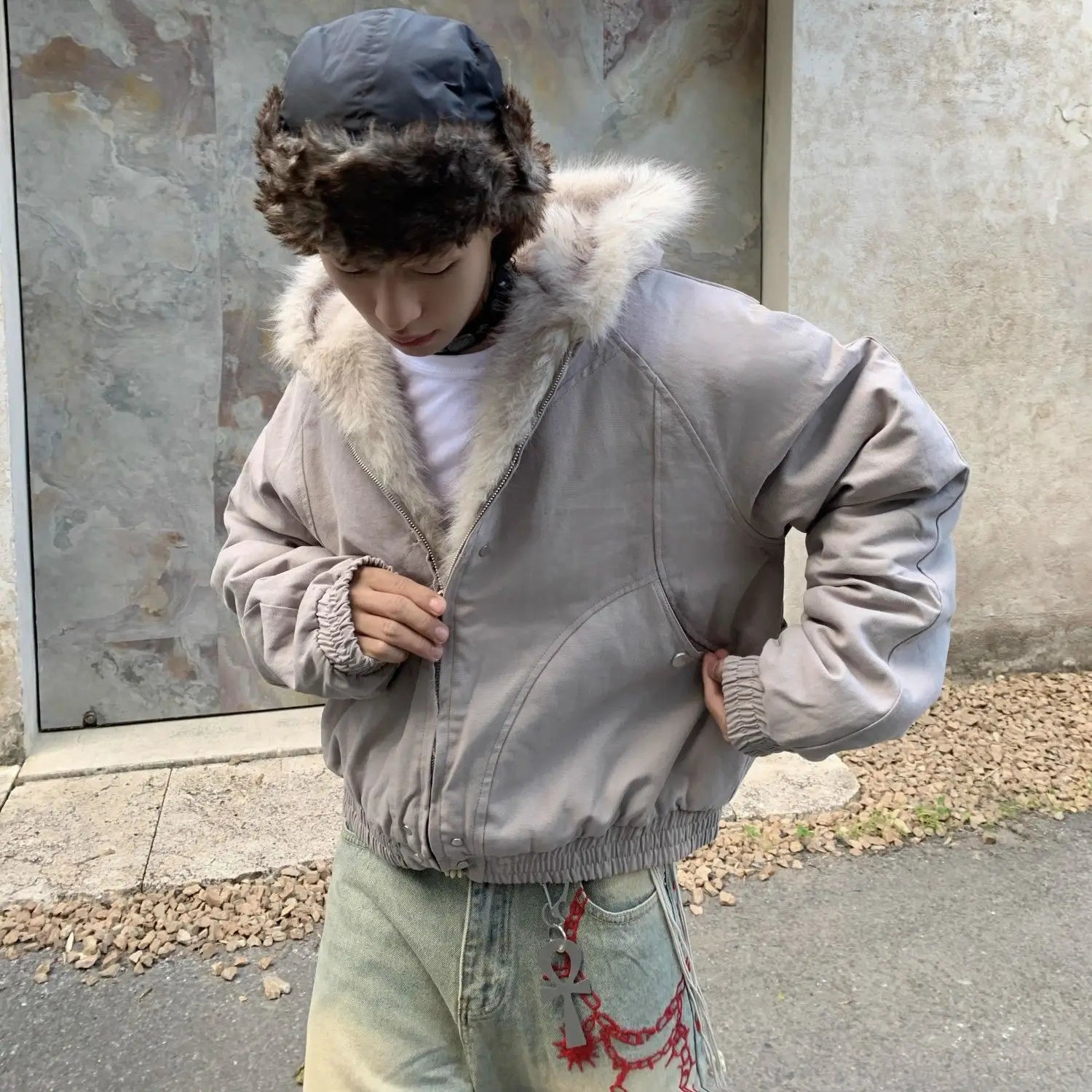 VOIDWEAR™ VDR_25 — a unisex oversized plush hooded jacket. Person wearing a gray jacket with fur hood standing outdoors.