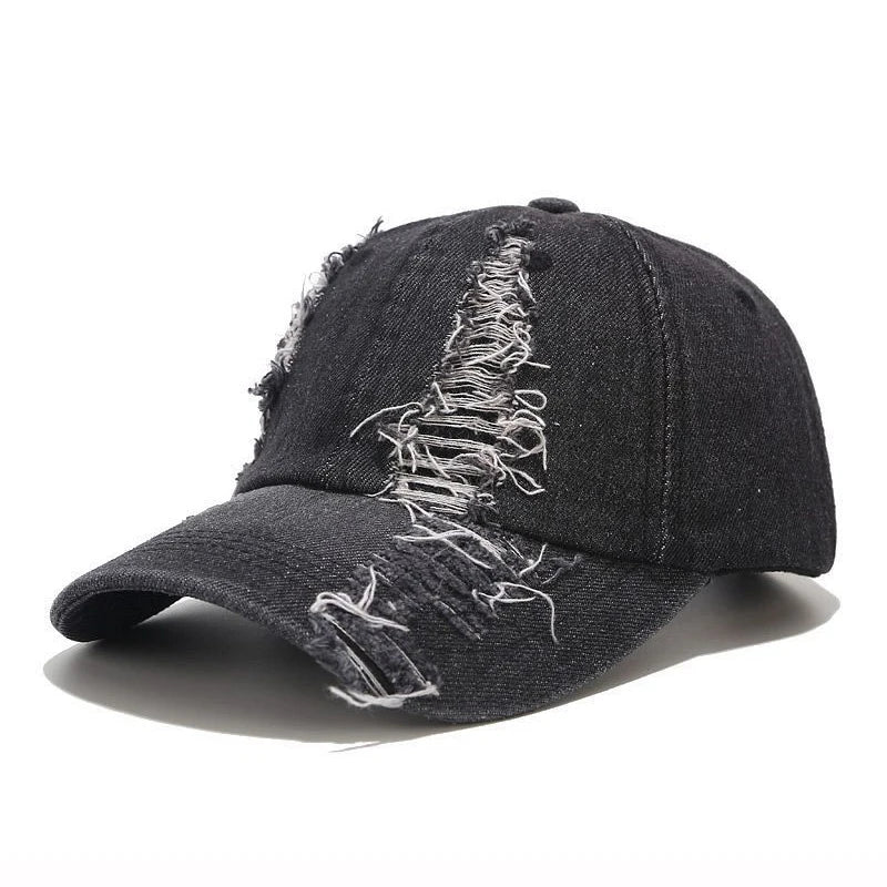 Vintage washed denim snapback by VOIDWEAR with distressed holes, ritual glyph detailing, and adjustable strap, designed for all-season streetwear.. Black denim cap with white distressed design on a white background
