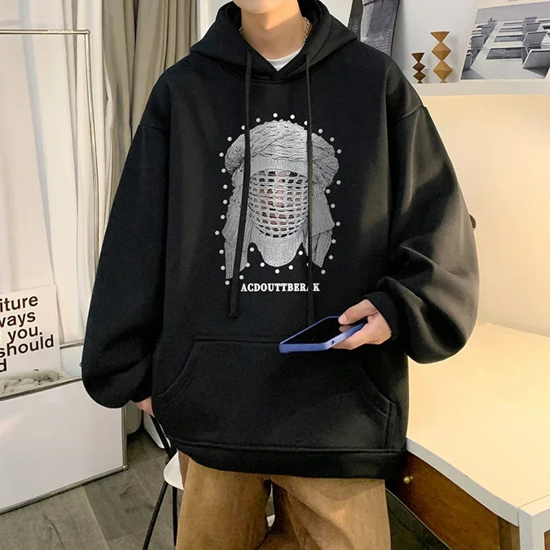VOIDWEAR VDR_SHDW_07 oversized goth hoodie with masked figure graphic, in black, styled in urban streetwear fit. Person wearing a black hoodie with a graphic design, holding a phone indoors.