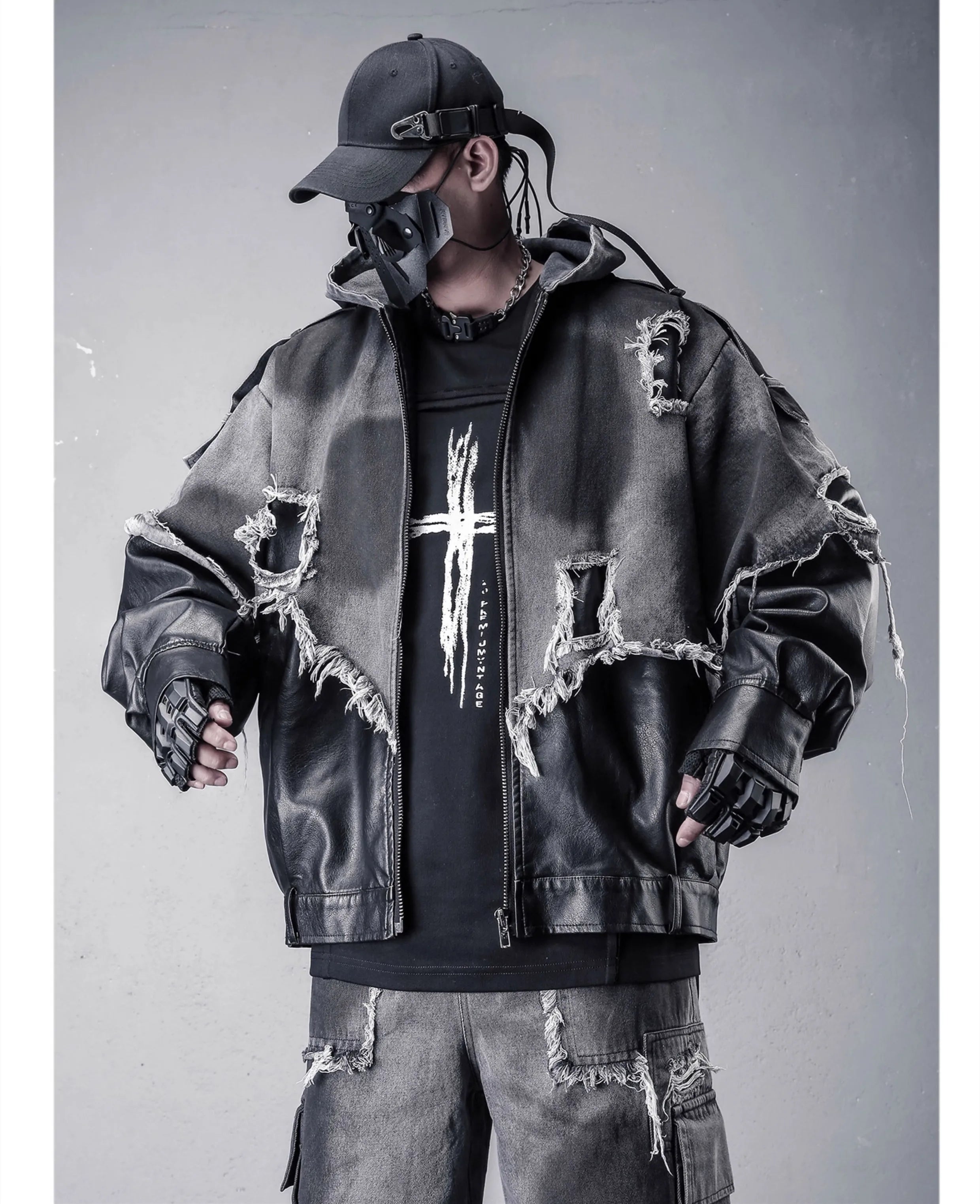 VOIDWEAR VDR_VANISH_05 jacket — ritual-inspired denim and PU leather techwear with vanish-mode hood and shadow-motion design. Person wearing a distressed jacket, black gloves, and a cap on a gray background