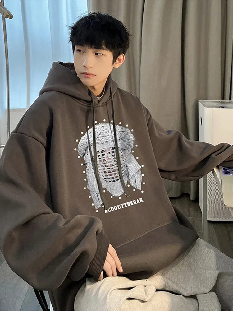 VOIDWEAR VDR_SHDW_07 oversized goth hoodie with masked figure graphic, in black, styled in urban streetwear fit. Person wearing a brown hoodie with a graphic design indoors