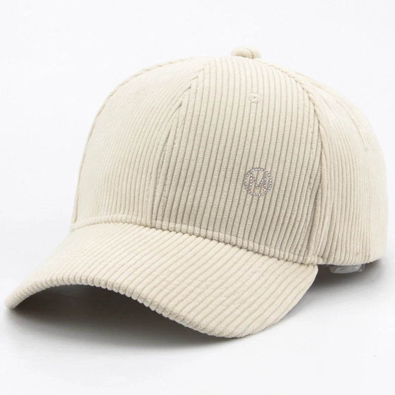 Diamond-studded M-letter corduroy baseball cap in solid color with adjustable strap, unisex streetwear headwear by VOIDWEAR.. Beige corduroy cap on a white background