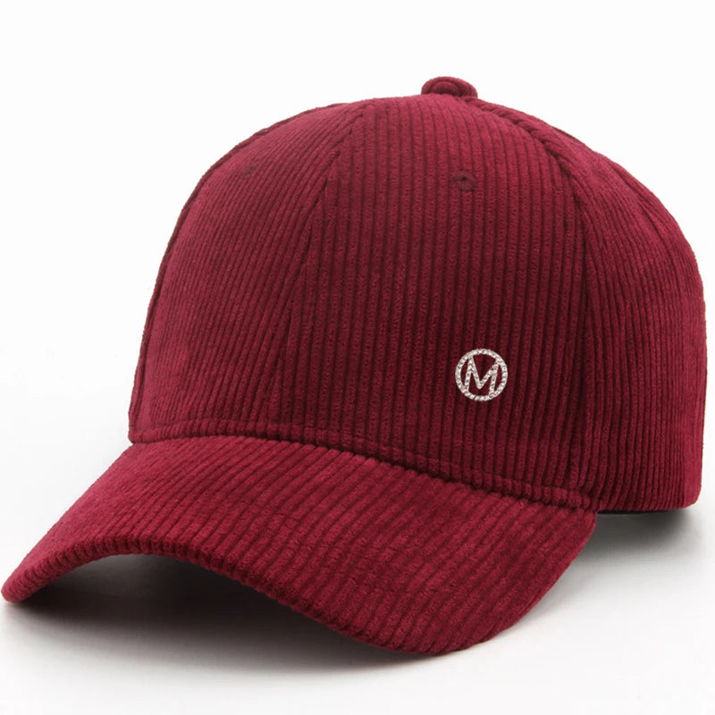 Diamond-studded M-letter corduroy baseball cap in solid color with adjustable strap, unisex streetwear headwear by VOIDWEAR.. Maroon corduroy cap with a white logo on a white background