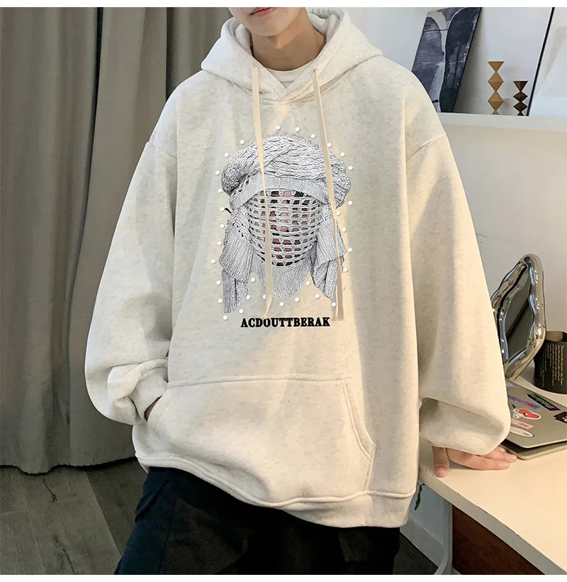 VOIDWEAR VDR_SHDW_07 oversized goth hoodie with masked figure graphic, in black, styled in urban streetwear fit. Person wearing a light gray hoodie with a graphic design in an indoor setting
