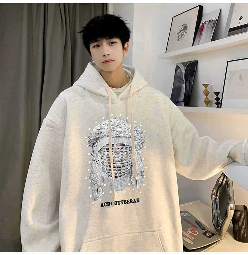 VOIDWEAR VDR_SHDW_07 oversized goth hoodie with masked figure graphic, in black, styled in urban streetwear fit. Person wearing a light gray hoodie with a graphic design in a room.