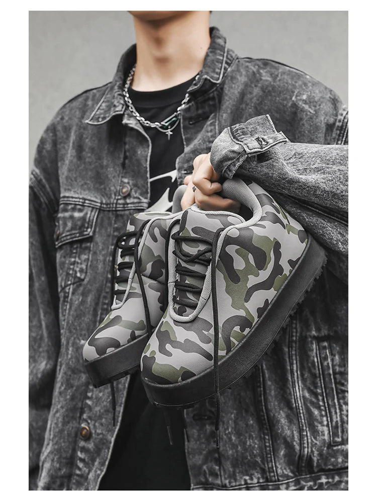 Person holding a pair of camouflage sneakers with a denim jacket. VOIDWEAR CODE_SYSTEM_07 ⚔️ chunky sneaker-style boots shown on a city street in winter, highlighting the microfiber leather upper and thick platform sole.