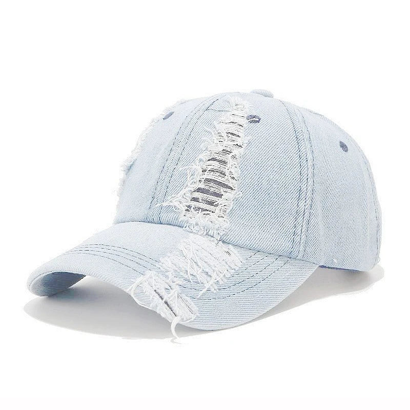 Vintage washed denim snapback by VOIDWEAR with distressed holes, ritual glyph detailing, and adjustable strap, designed for all-season streetwear. Light blue denim cap with distressed details on a white background
