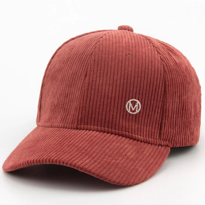 Diamond-studded M-letter corduroy baseball cap in solid color with adjustable strap, unisex streetwear headwear by VOIDWEAR.. Red corduroy cap with a white logo on a white background