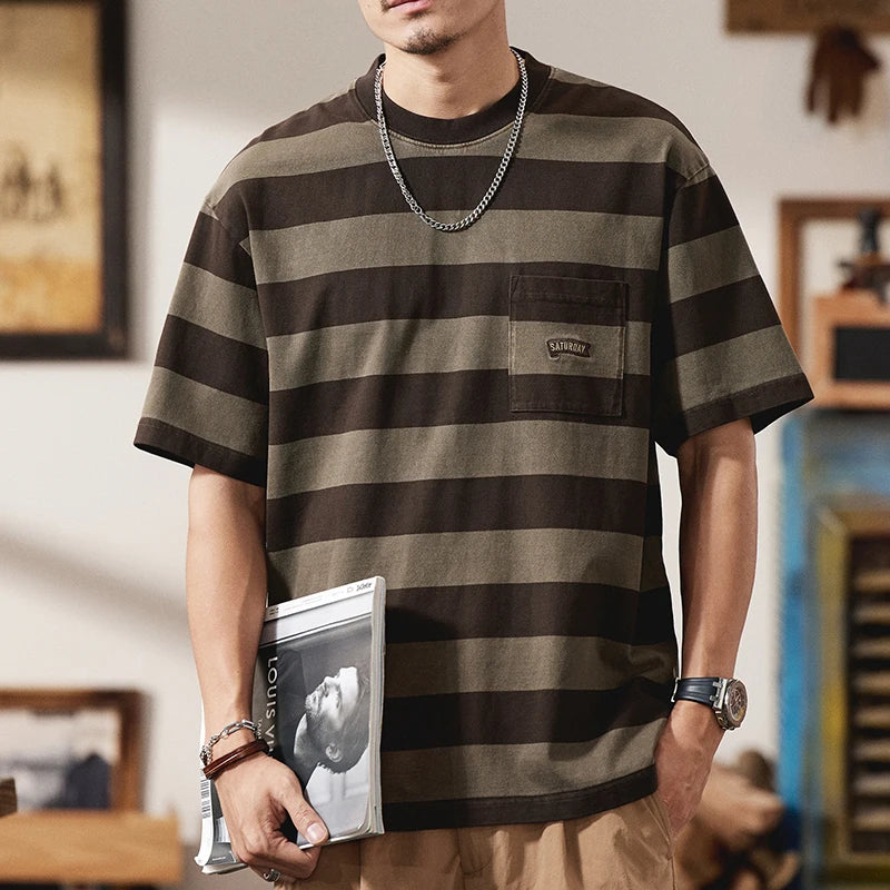 VOIDWEAR striped oversized tee with vanish-mode system, 100% cotton, summer streetwear. Person wearing a brown and black striped t-shirt with a visible brand logo, holding a magazine.