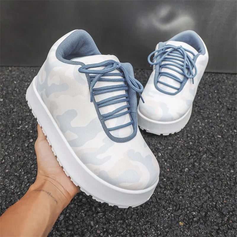 White sneakers with blue laces held by a hand on a dark asphalt surface. VOIDWEAR CODE_SYSTEM_07 ⚔️ chunky sneaker-style boots shown on a city street in winter, highlighting the microfiber leather upper and thick platform sole.