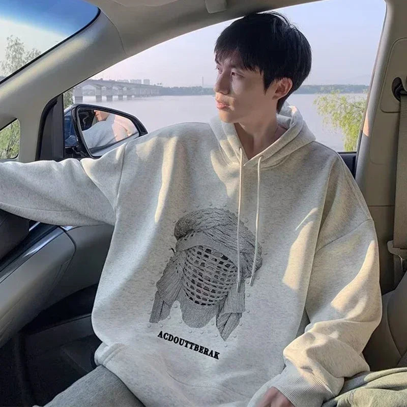 VOIDWEAR VDR_SHDW_07 oversized goth hoodie with masked figure graphic, in black, styled in urban streetwear fit. Person wearing a hoodie with a graphic design sitting inside a car.